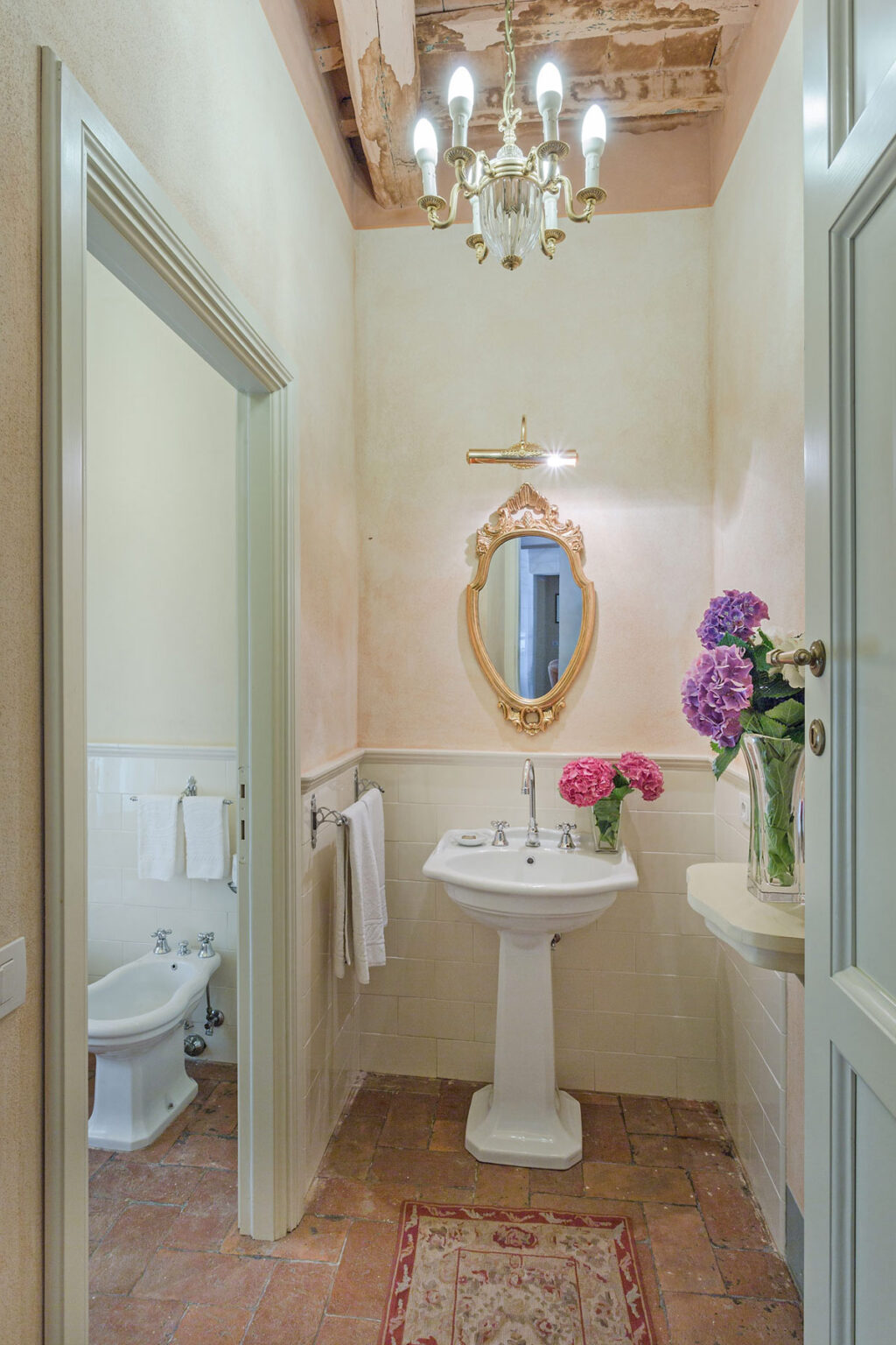 Elegant bathroom featuring a vintage-style mirror, floral arrangements, and soft pastel wall colors, creating a serene atmosphere. | Only on SopranoVillas