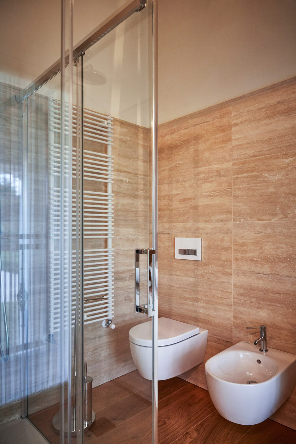 Modern bathroom interior featuring a glass shower enclosure, sleek chrome fixtures, and warm-toned tiled walls, highlighting a contemporary design aesthetic. | Only on SopranoVillas