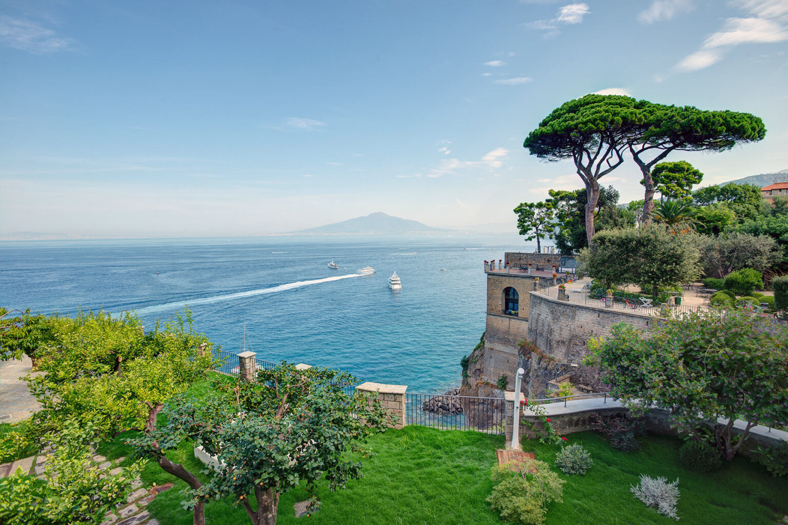 Scenic view of the coastline with lush greenery, overlooking the blue waters and a distant mountain, ideal for travel and nature enthusiasts. | Only on SopranoVillas