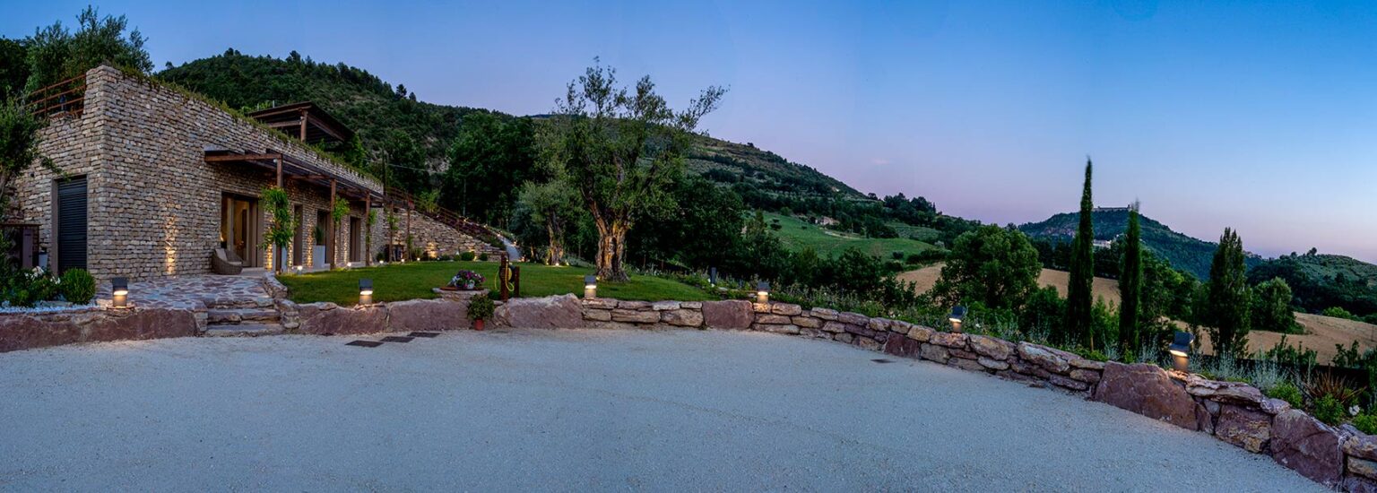 Scenic view of a tranquil landscape featuring a stone patio, lush greenery, and distant hills under a twilight sky, ideal for relaxation and outdoor gatherings. | Only on SopranoVillas