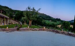 Scenic view of a tranquil landscape featuring a stone patio, lush greenery, and distant hills under a twilight sky, ideal for relaxation and outdoor gatherings.