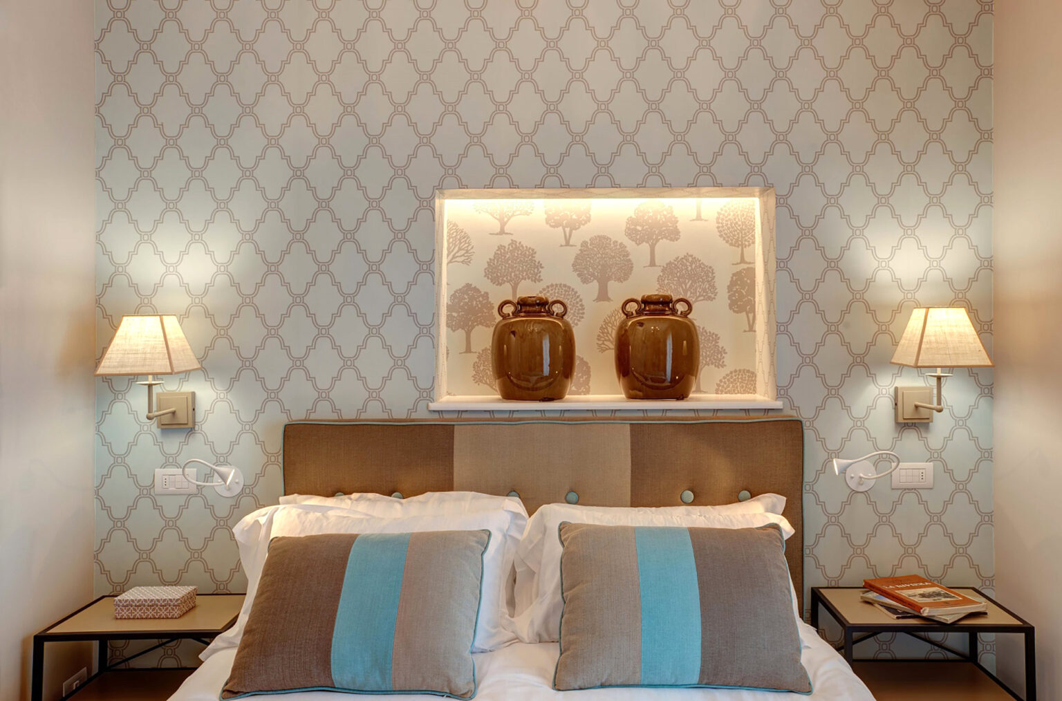 Elegant bedroom featuring a stylish headboard, decorative wall with a subtle pattern, two bedside lamps, and two decorative vases on a shelf, creating a cozy and inviting atmosphere. | Only on SopranoVillas