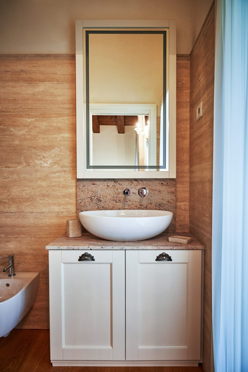 Modern bathroom design featuring a sleek, round white sink on a wooden countertop, complemented by a stylish mirror above. The warm wood paneling adds a touch of elegance to the space. | Only on SopranoVillas