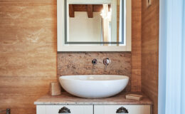Modern bathroom design featuring a sleek, round white sink on a wooden countertop, complemented by a stylish mirror above. The warm wood paneling adds a touch of elegance to the space.