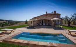 Luxurious stone villa with a swimming pool and sun loungers, set in a picturesque landscape under a clear blue sky. Ideal for vacation rentals and outdoor relaxation.