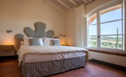 Cozy and stylish bedroom featuring a unique headboard design, large windows with scenic views, and soft bedding, perfect for relaxation and comfort.