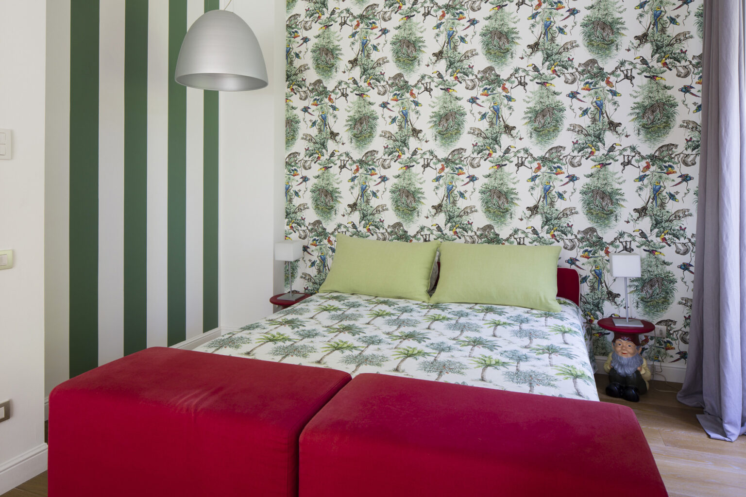 Cozy bedroom featuring a floral wallpaper accent wall, green bedding, and a red ottoman, creating a vibrant and inviting atmosphere. | Only on SopranoVillas