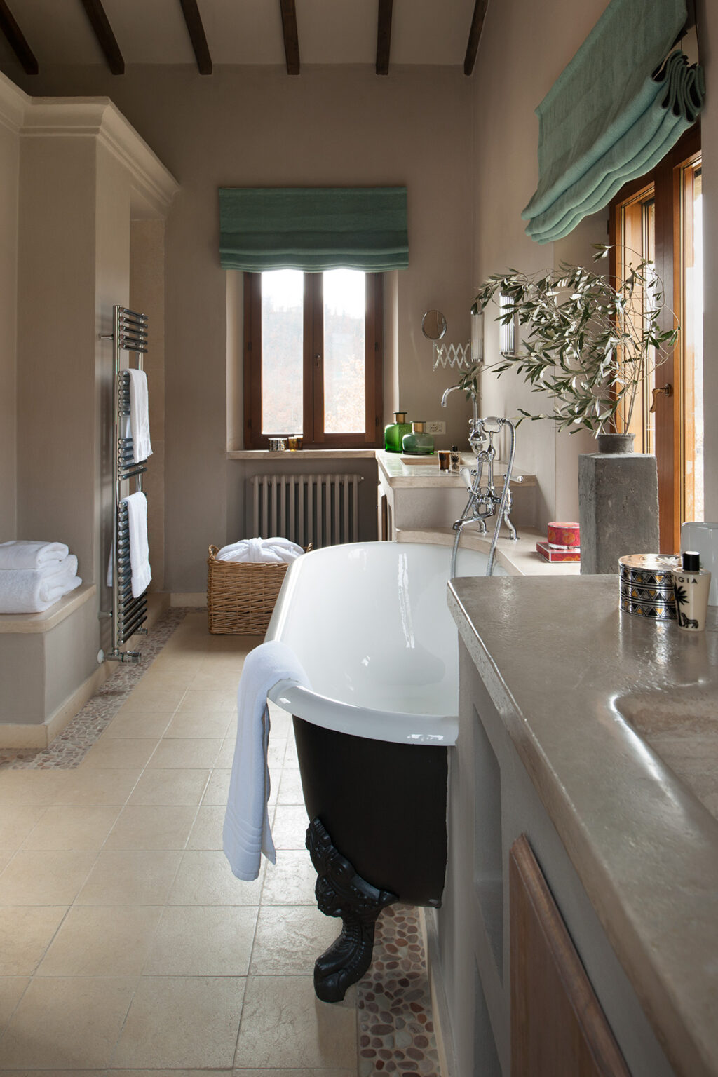 Modern bathroom featuring a freestanding bathtub, stone countertop, and natural light from a window. Soft towels are neatly arranged, with a woven basket for storage, creating a serene and inviting atmosphere. | Only on SopranoVillas