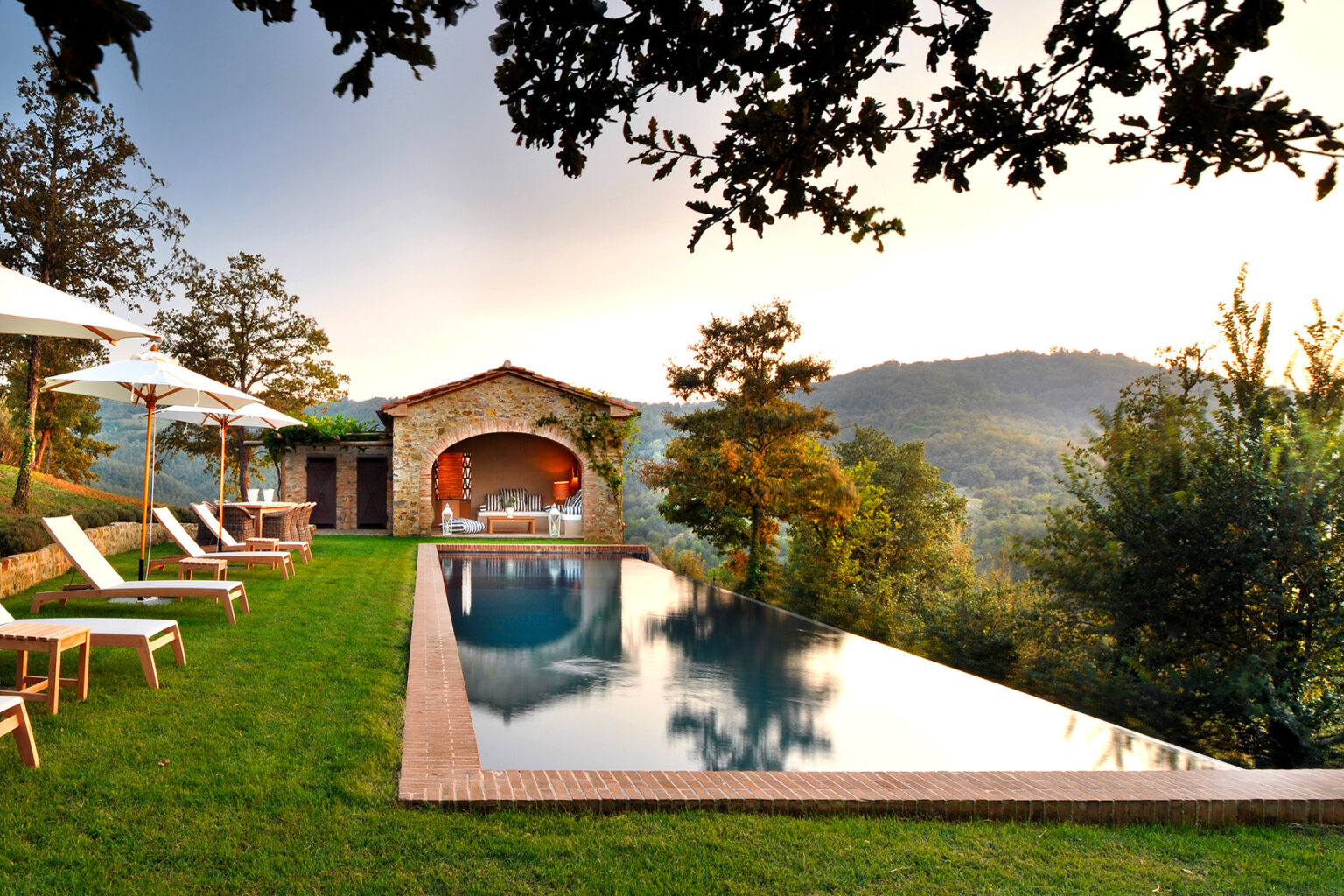 Luxury villa with infinity pool overlooking scenic mountains, surrounded by lush greenery and sun loungers, perfect for relaxation and outdoor living. | Only on SopranoVillas