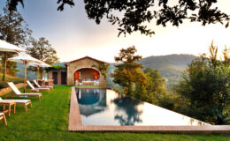 Luxury villa with infinity pool overlooking scenic mountains, surrounded by lush greenery and sun loungers, perfect for relaxation and outdoor living.