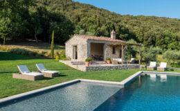 Stone villa with a pool surrounded by lush greenery, featuring sun loungers and a scenic hillside backdrop. Perfect for a relaxing getaway in nature.