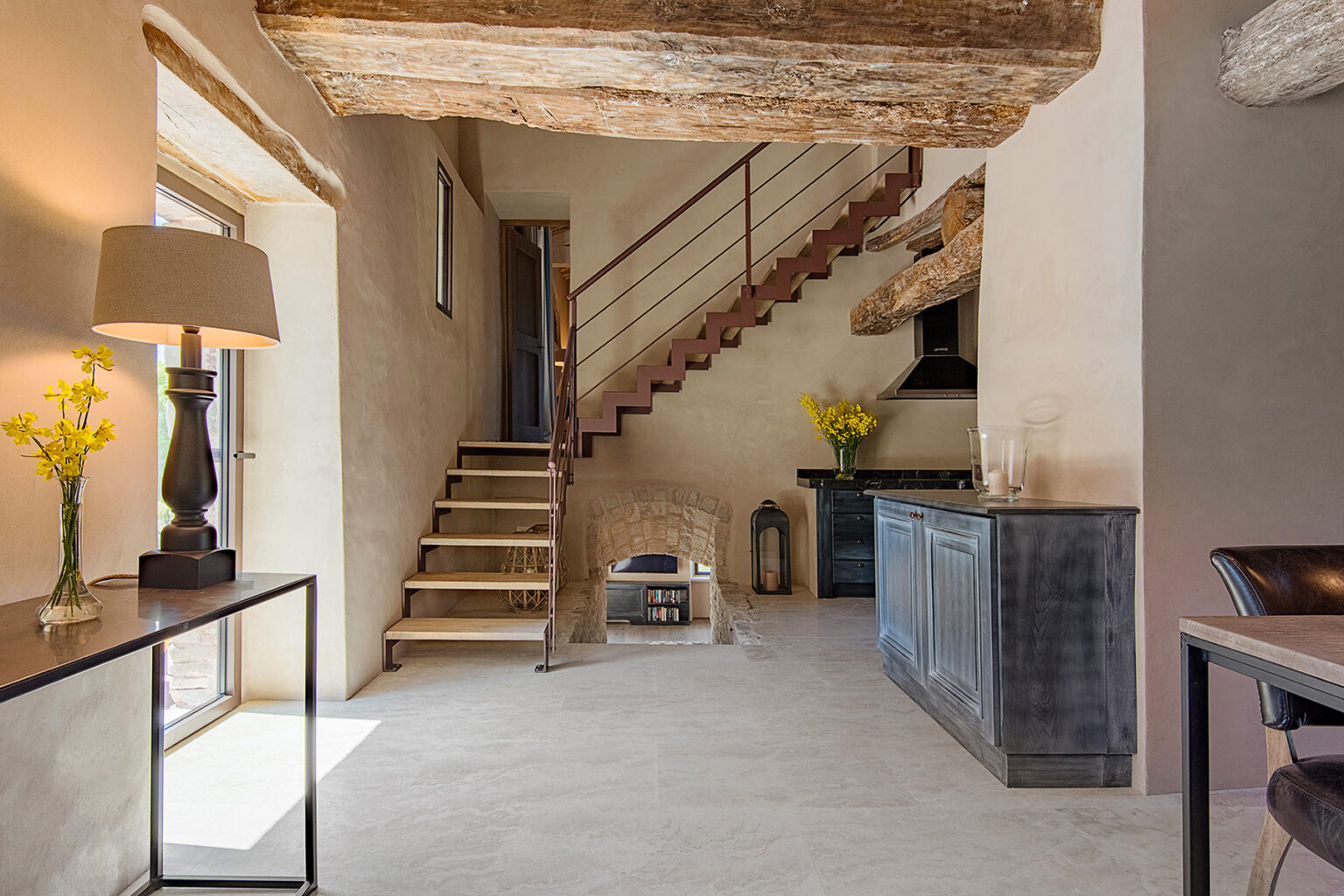 Modern interior design of a spacious entryway featuring a wooden staircase, stylish lamp, and decorative flowers. The neutral color palette and natural light create a warm and inviting atmosphere. | Only on SopranoVillas