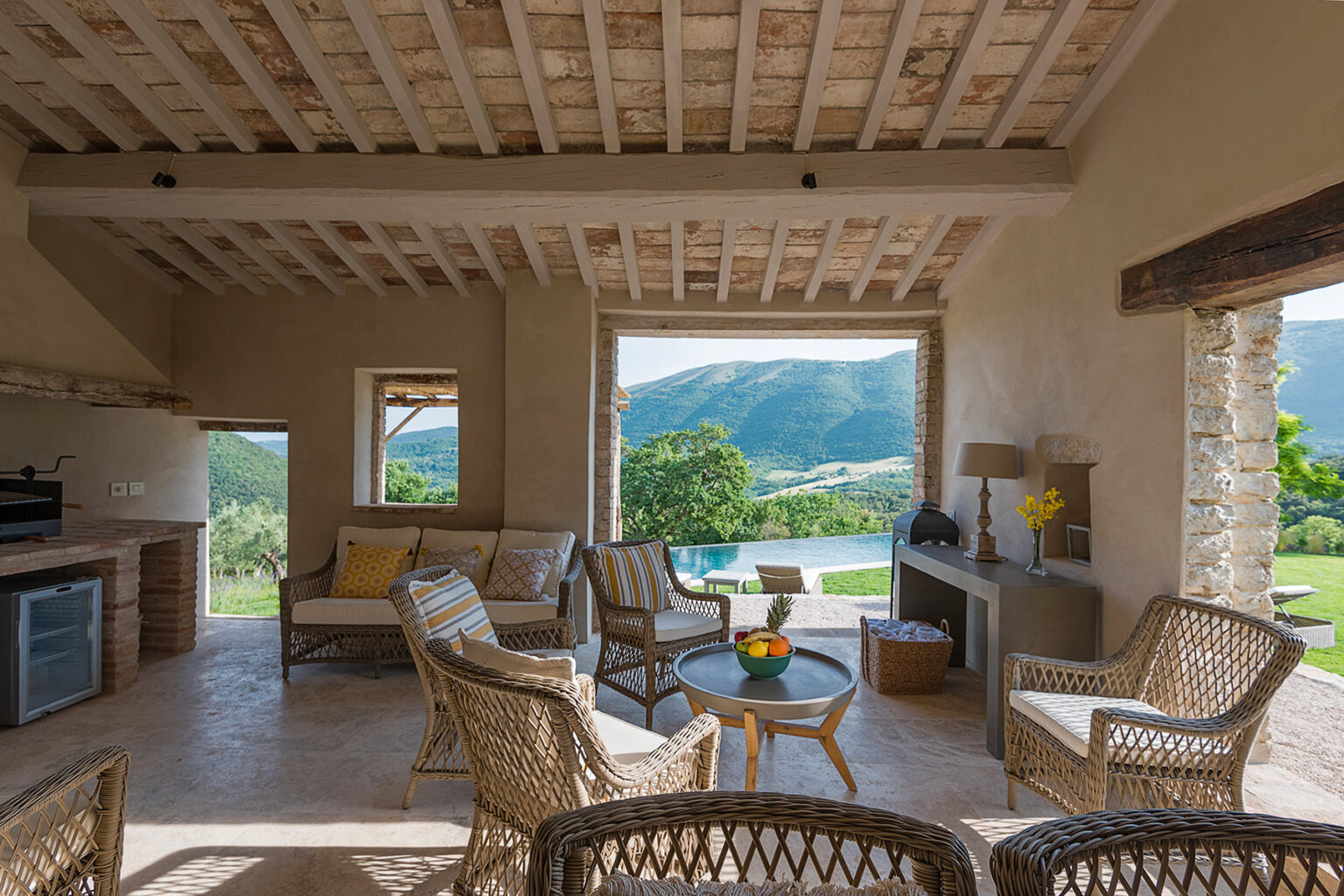 Cozy interior of a modern rustic living space featuring woven furniture, large windows with scenic mountain views, and an open layout that enhances natural light. | Only on SopranoVillas