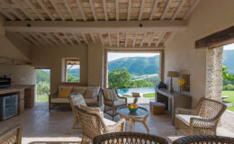 Cozy interior of a modern rustic living space featuring woven furniture, large windows with scenic mountain views, and an open layout that enhances natural light.