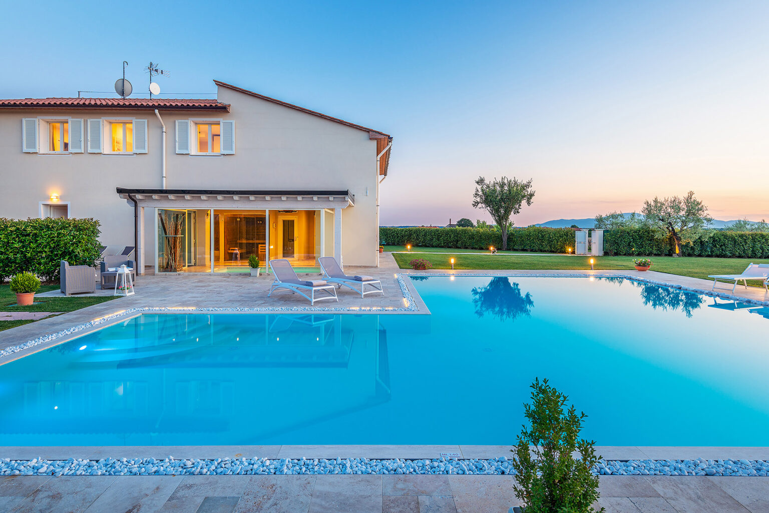 Luxurious villa with a sparkling swimming pool, surrounded by lush greenery and a serene landscape at sunset. Ideal for relaxation and outdoor entertaining. | Only on SopranoVillas