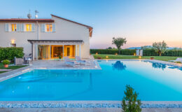 Luxurious villa with a sparkling swimming pool, surrounded by lush greenery and a serene landscape at sunset. Ideal for relaxation and outdoor entertaining.