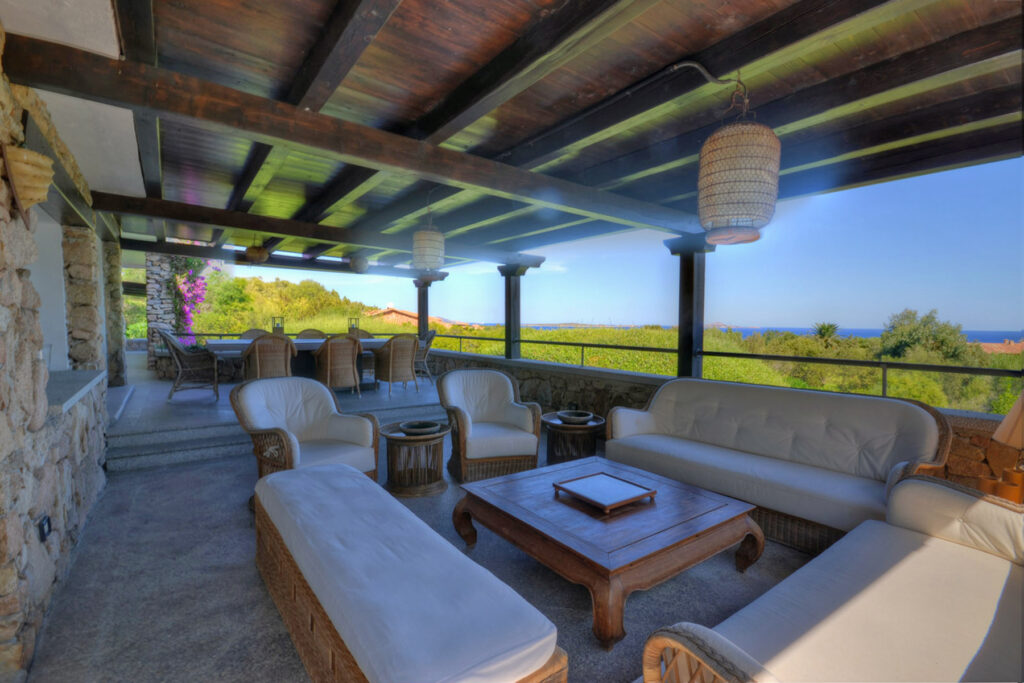Spacious outdoor living area with comfortable seating, wooden coffee table, and scenic views of lush greenery and the ocean. Ideal for relaxation and entertaining. | Only on SopranoVillas