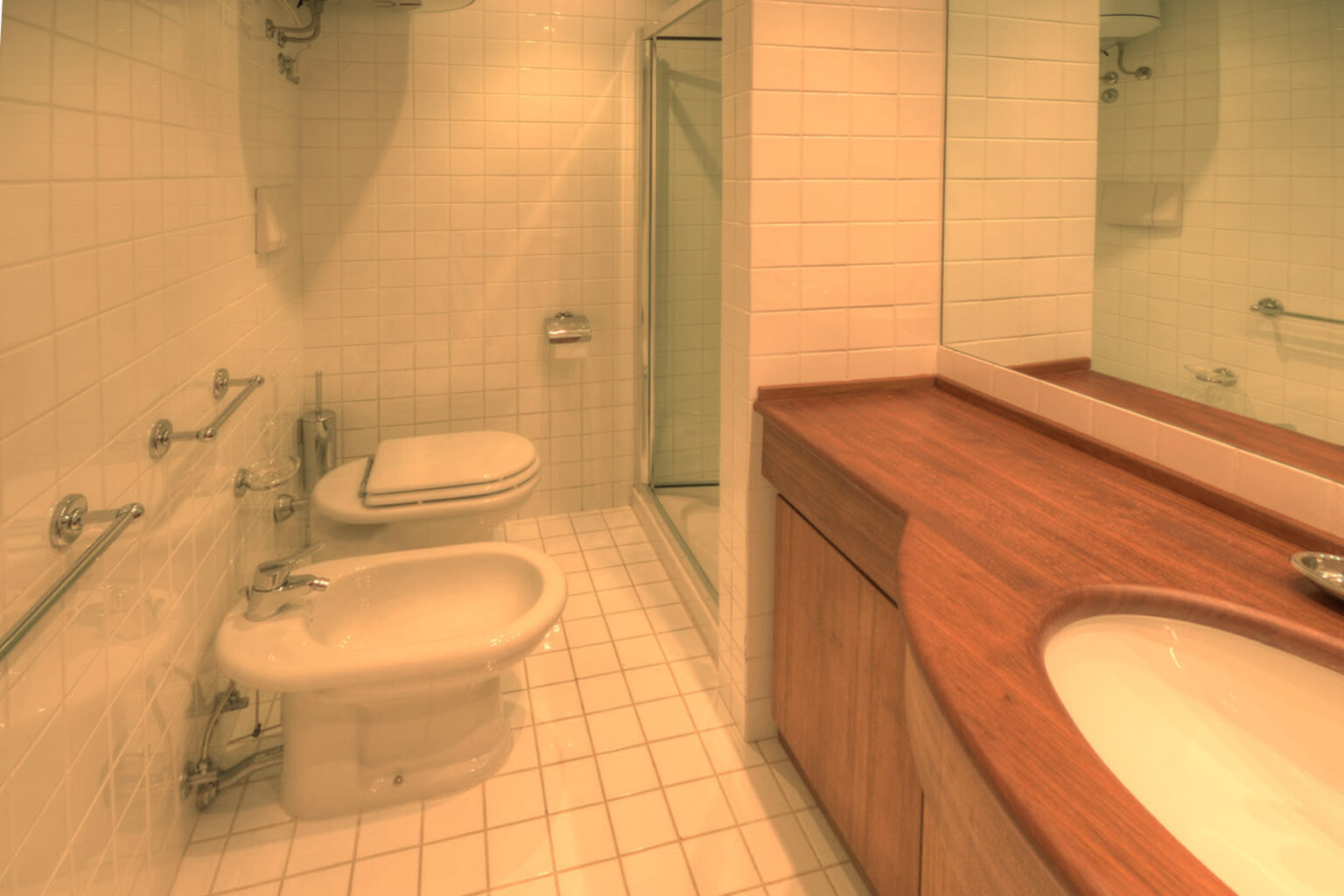 Modern bathroom design featuring a shower, bidet, toilet, and wooden vanity with a sink, set against tiled walls and floor. Ideal for showcasing contemporary interior aesthetics. | Only on SopranoVillas