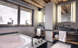 Luxurious modern bathroom featuring a freestanding bathtub, elegant marble countertops, and stylish wooden accents, with large windows offering scenic views and natural light.