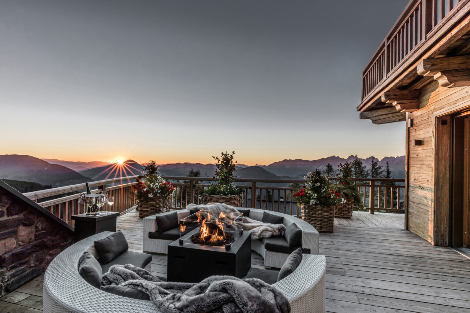Mountain view deck with a cozy fire pit, surrounded by comfortable seating and potted plants, showcasing a stunning sunset over the peaks. | Only on SopranoVillas
