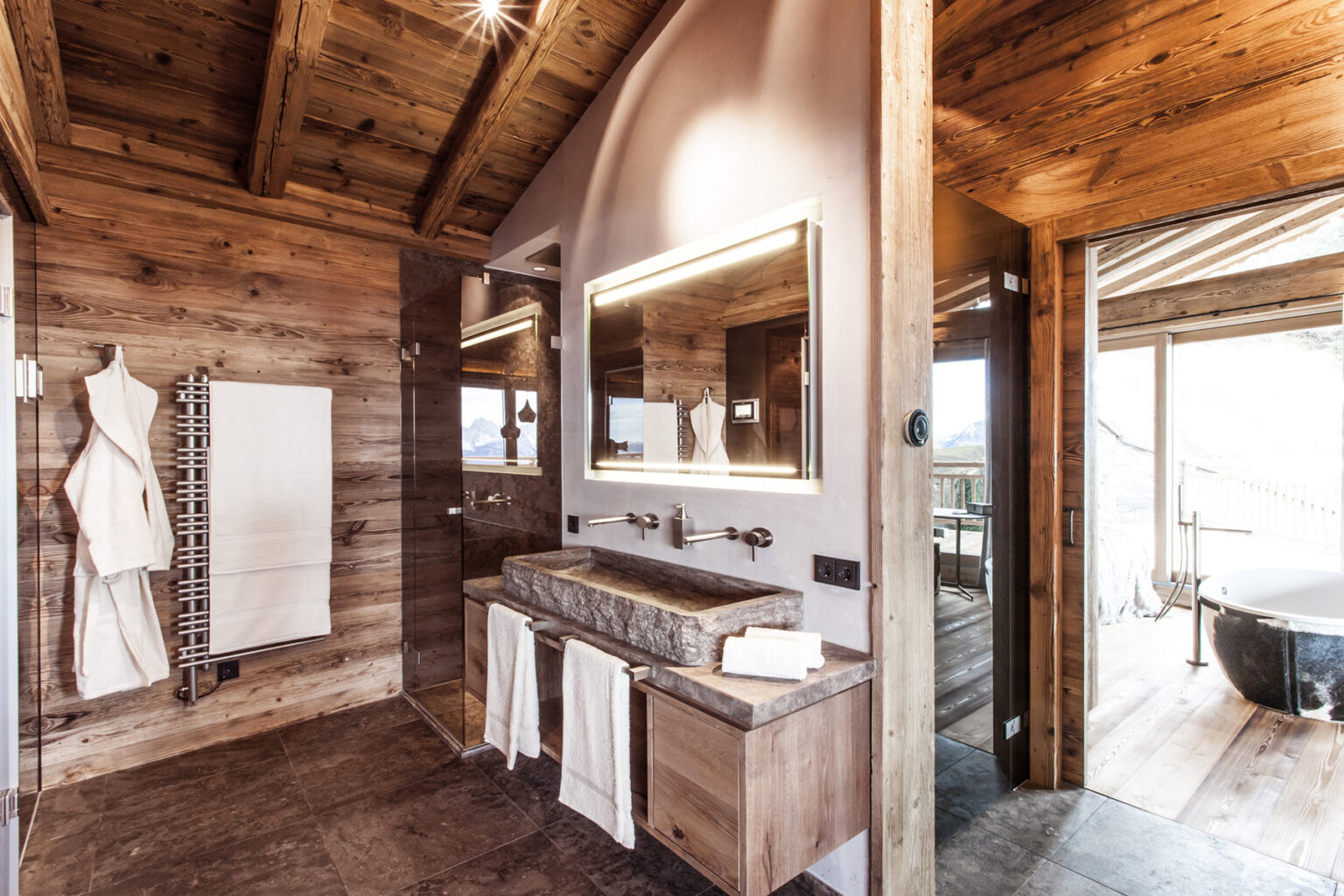 Modern rustic bathroom design featuring wooden accents, double sinks, and a large mirror, with a cozy atmosphere and natural light streaming in. | Only on SopranoVillas