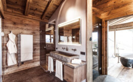 Modern rustic bathroom design featuring wooden accents, double sinks, and a large mirror, with a cozy atmosphere and natural light streaming in.