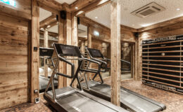 Modern home gym featuring two treadmills and wooden decor, designed for fitness enthusiasts. Mirrors enhance the spacious feel, creating an inviting workout environment.