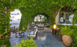 Luxurious outdoor patio surrounded by lush greenery, featuring comfortable seating and a stunning ocean view. Ideal for relaxation and entertaining in a serene environment.