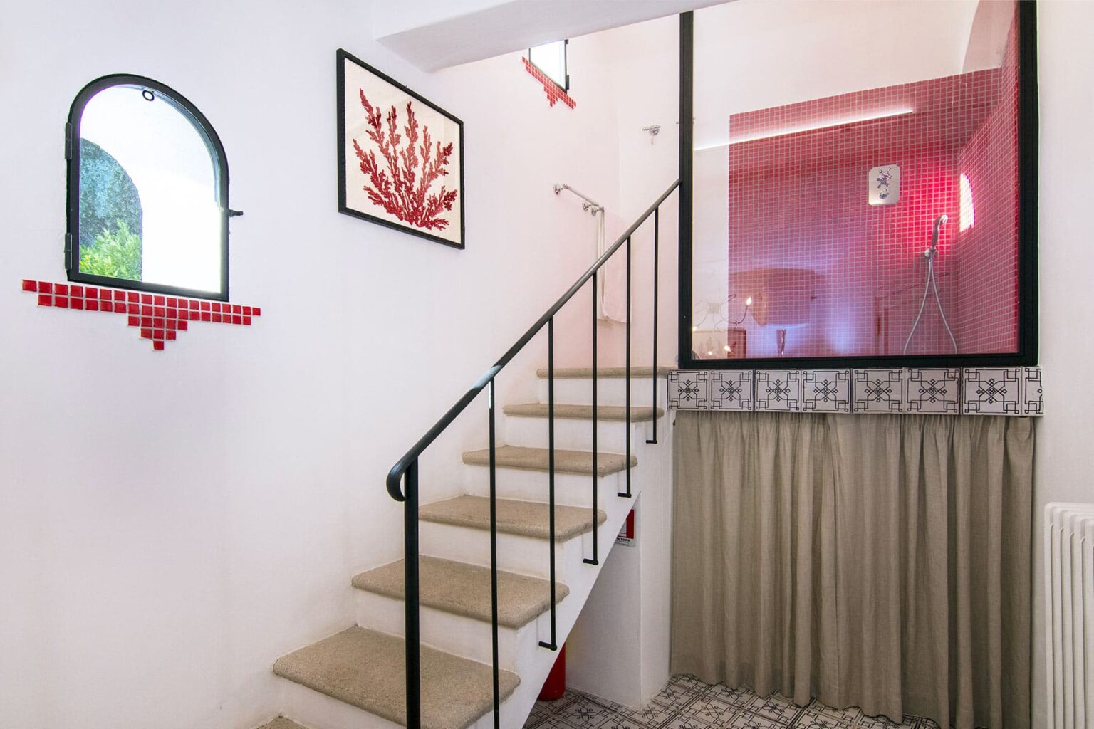 Modern staircase with a decorative wall featuring red accents and artwork, leading to a stylish upper level in a contemporary home. The interior design combines clean lines with vibrant colors, creating an inviting atmosphere. | Only on SopranoVillas