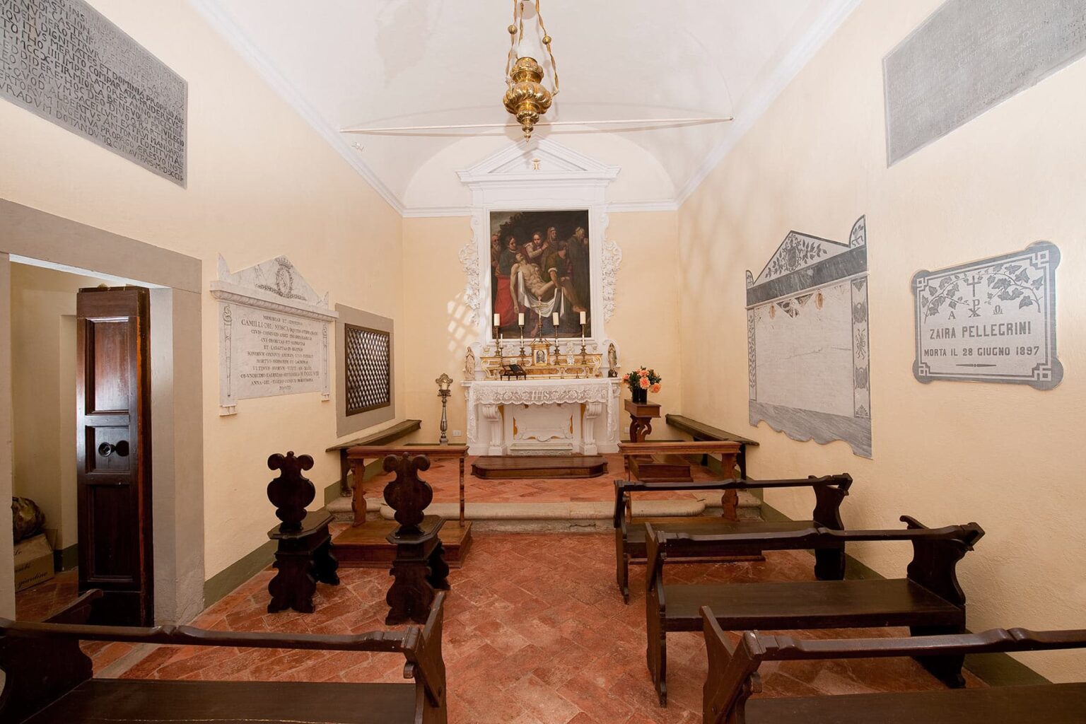 Interior view of a small, historic chapel featuring a central altar, wooden benches, and religious artwork on the walls. The serene atmosphere is enhanced by soft lighting and decorative elements, reflecting traditional architectural style. | Only on SopranoVillas