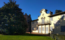 Historic villa with a yellow facade and decorative architecture, surrounded by lush greenery and a clear blue sky. Ideal for showcasing architectural beauty and landscape design.