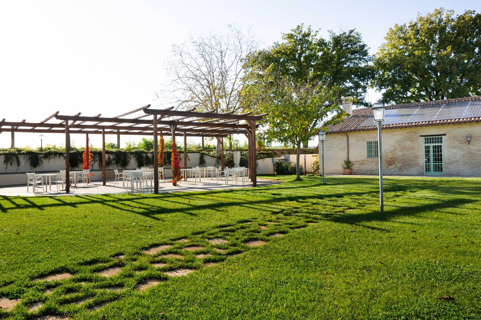 Outdoor event space featuring a pergola and well-maintained lawn, with a rustic building in the background, perfect for gatherings and celebrations. | Only on SopranoVillas