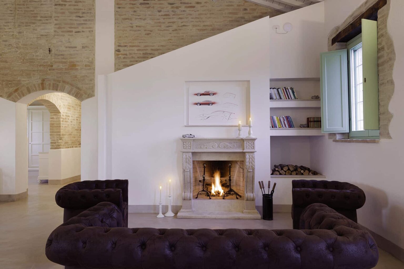 Cozy living room featuring a stone fireplace, elegant dark sofa, and natural light streaming through a green window. Perfect for a warm and inviting atmosphere. | Only on SopranoVillas