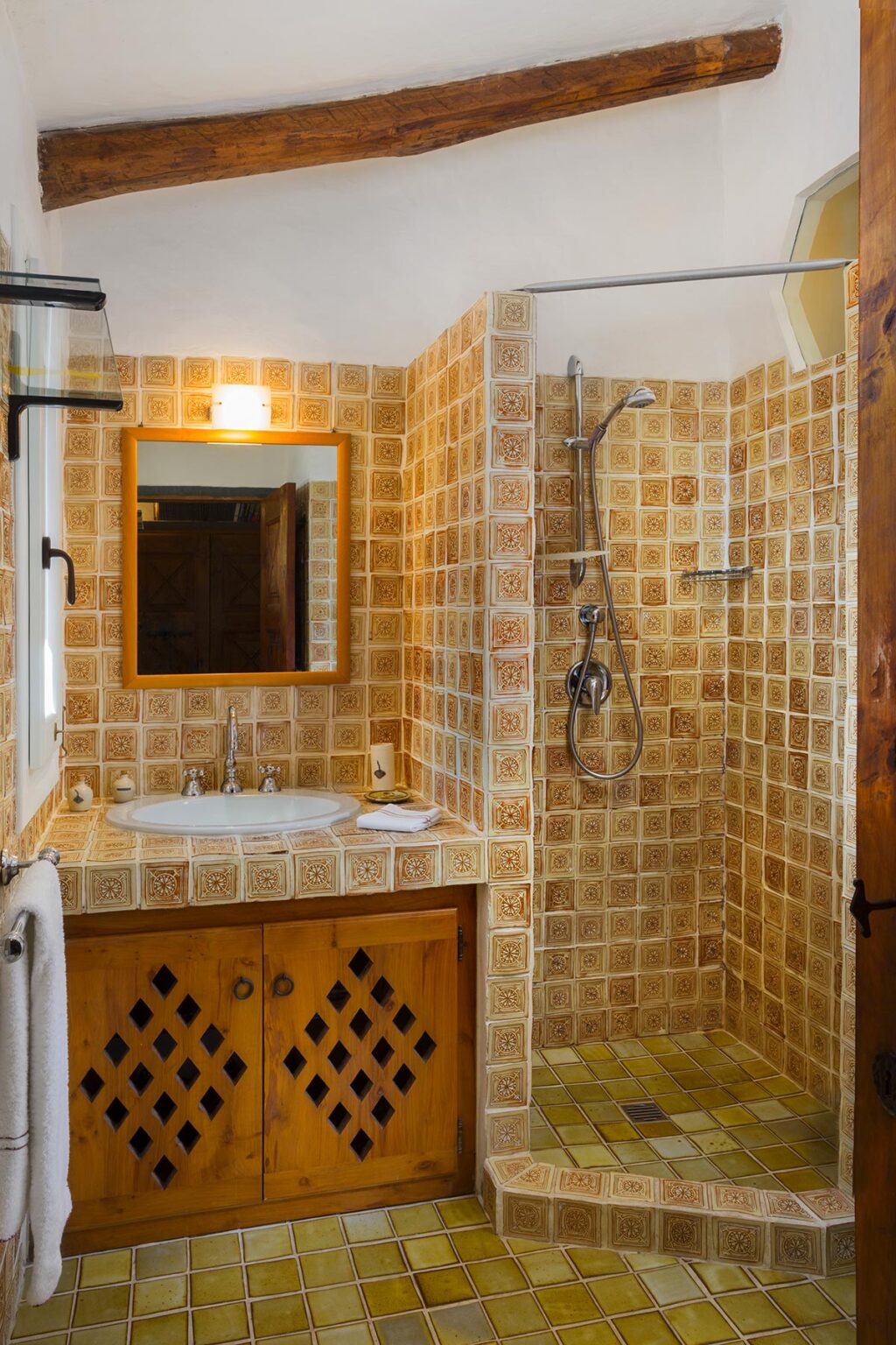 Modern bathroom interior featuring a tiled shower, sink with wooden cabinetry, and a large mirror, designed for comfort and style. | Only on SopranoVillas