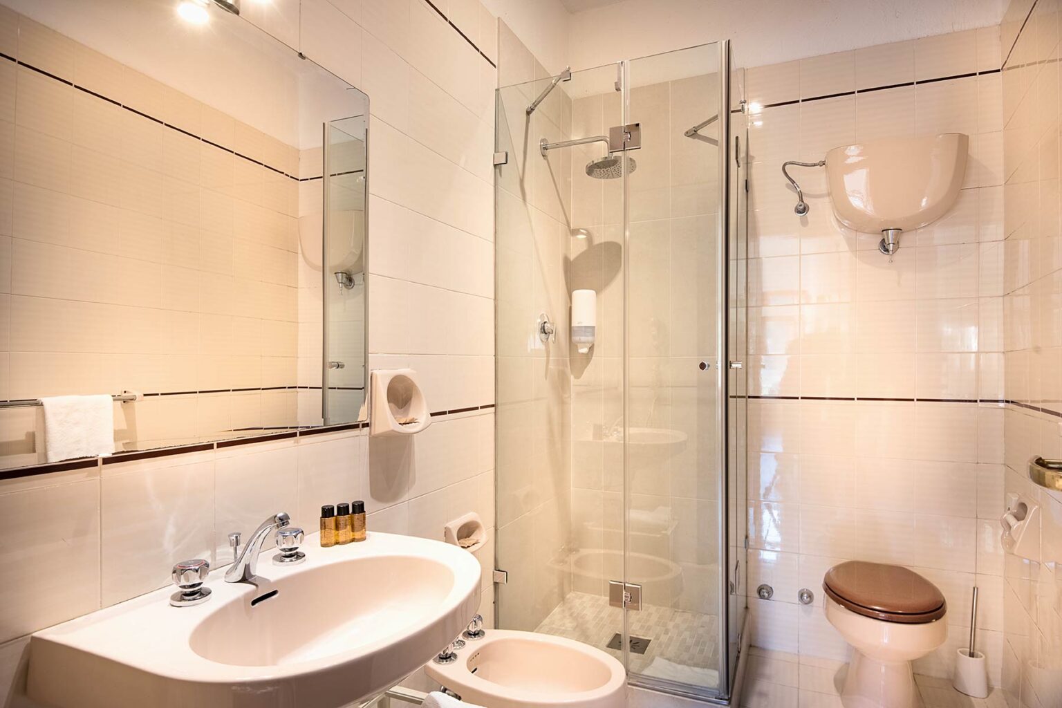 Modern bathroom featuring a glass shower enclosure, a stylish oval sink, and a large mirror, complemented by neutral-colored tiles and elegant fixtures. Ideal for showcasing contemporary interior design in home improvement or real estate contexts. | Only on SopranoVillas