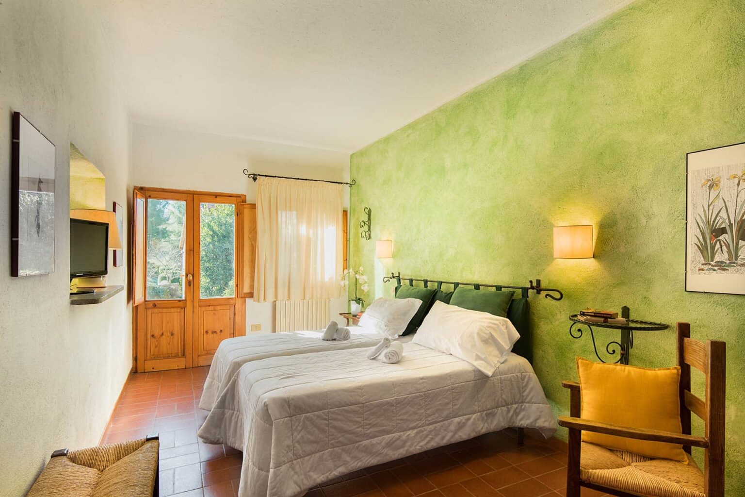 Cozy bedroom featuring twin beds with white linens, a vibrant green accent wall, wooden furniture, and large windows that provide natural light. Ideal for relaxation and comfort. | Only on SopranoVillas