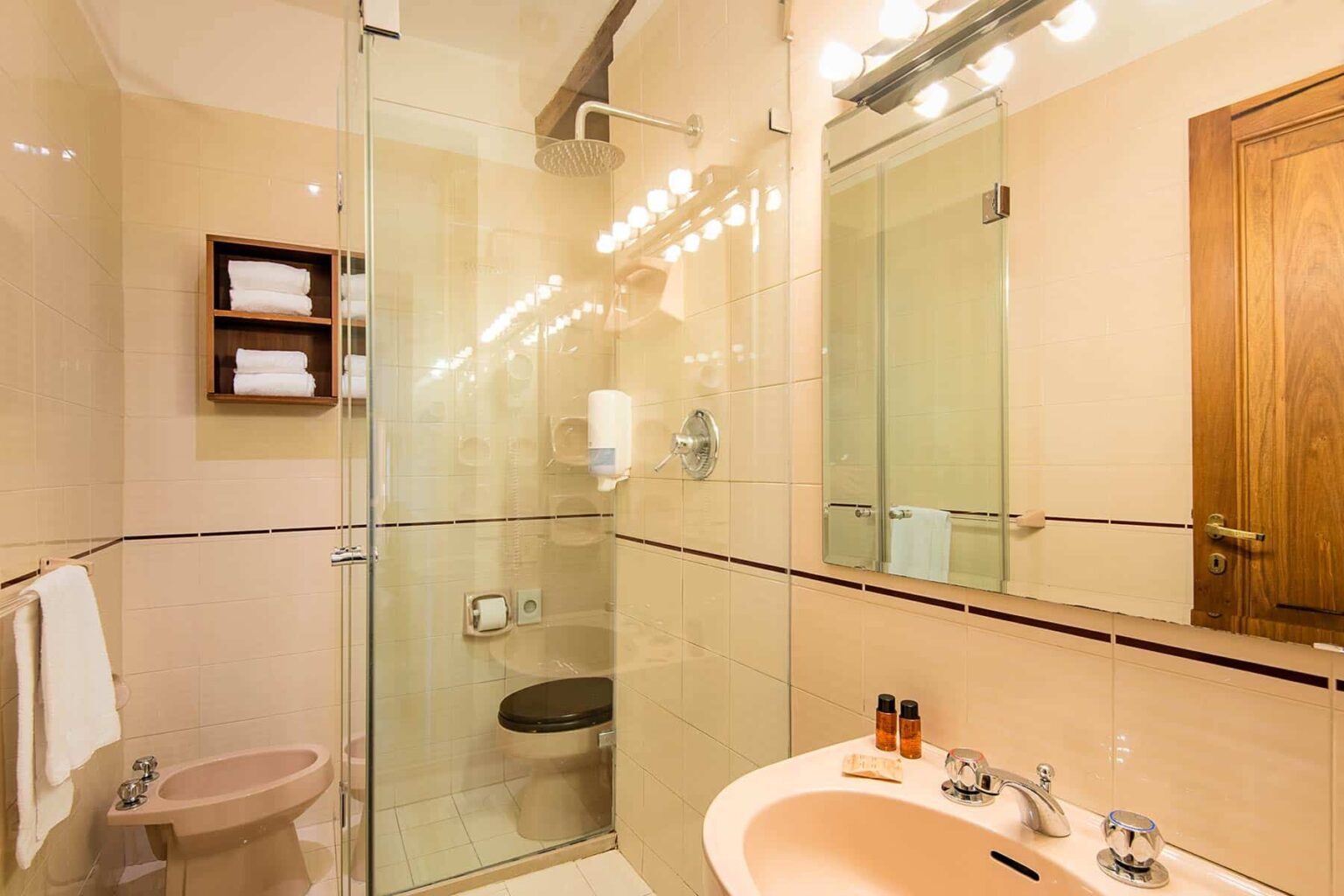 Modern bathroom featuring a glass shower enclosure, sink with vanity, and wooden accents, designed for comfort and style. | Only on SopranoVillas