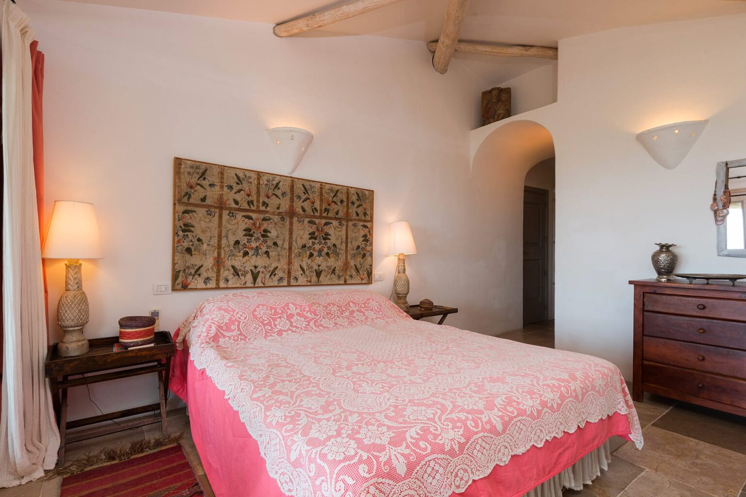 Cozy bedroom featuring a pink floral-patterned bedspread, wooden furniture, and soft lighting, creating a warm and inviting atmosphere. | Only on SopranoVillas