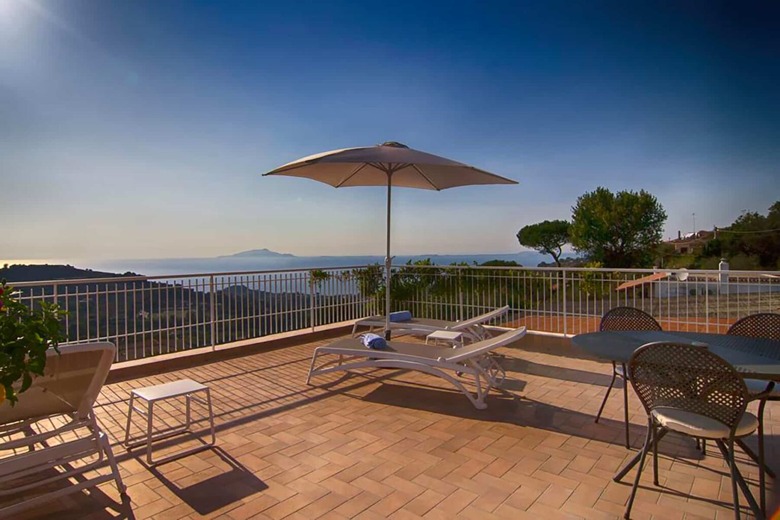 Scenic terrace with sun loungers and an umbrella overlooking a beautiful landscape and ocean view, ideal for relaxation and outdoor enjoyment. | Only on SopranoVillas