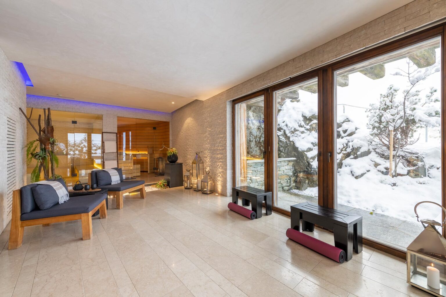 Modern wellness retreat interior featuring large windows with a snowy landscape, minimalist furniture, and a serene atmosphere. Ideal for relaxation and rejuvenation. | Only on SopranoVillas