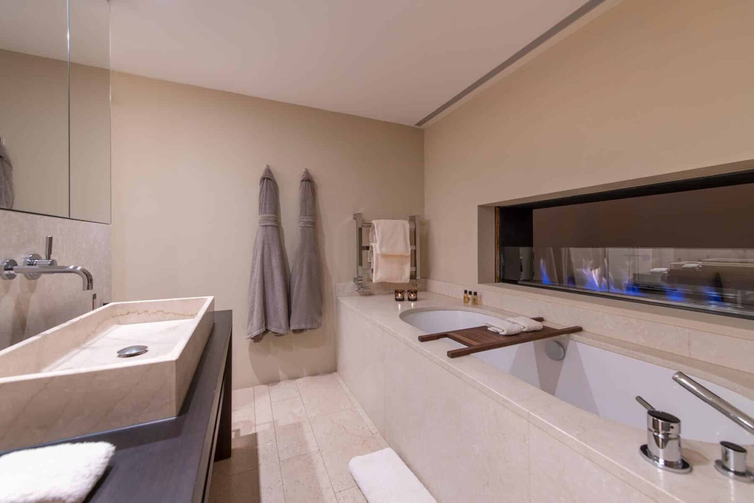 Modern bathroom interior featuring a stylish bathtub, sleek sink, and neutral color palette. The design includes elegant towels hanging on the wall and a large window that enhances natural light. Ideal for showcasing luxury home decor and contemporary bathroom aesthetics. | Only on SopranoVillas