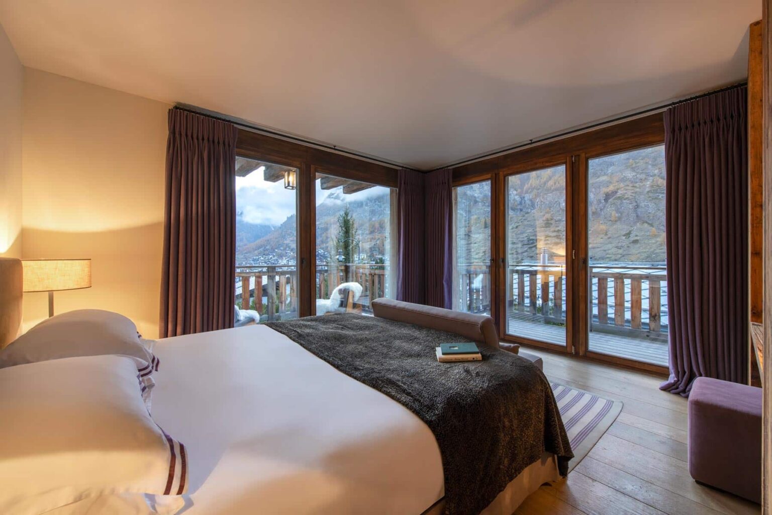 Cozy bedroom with large windows offering stunning mountain views, featuring a comfortable bed, modern decor, and warm lighting, ideal for a relaxing getaway. | Only on SopranoVillas