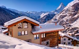 Snow-covered chalet in the Swiss Alps with a backdrop of the Matterhorn mountain, showcasing a picturesque winter landscape and charming alpine architecture.