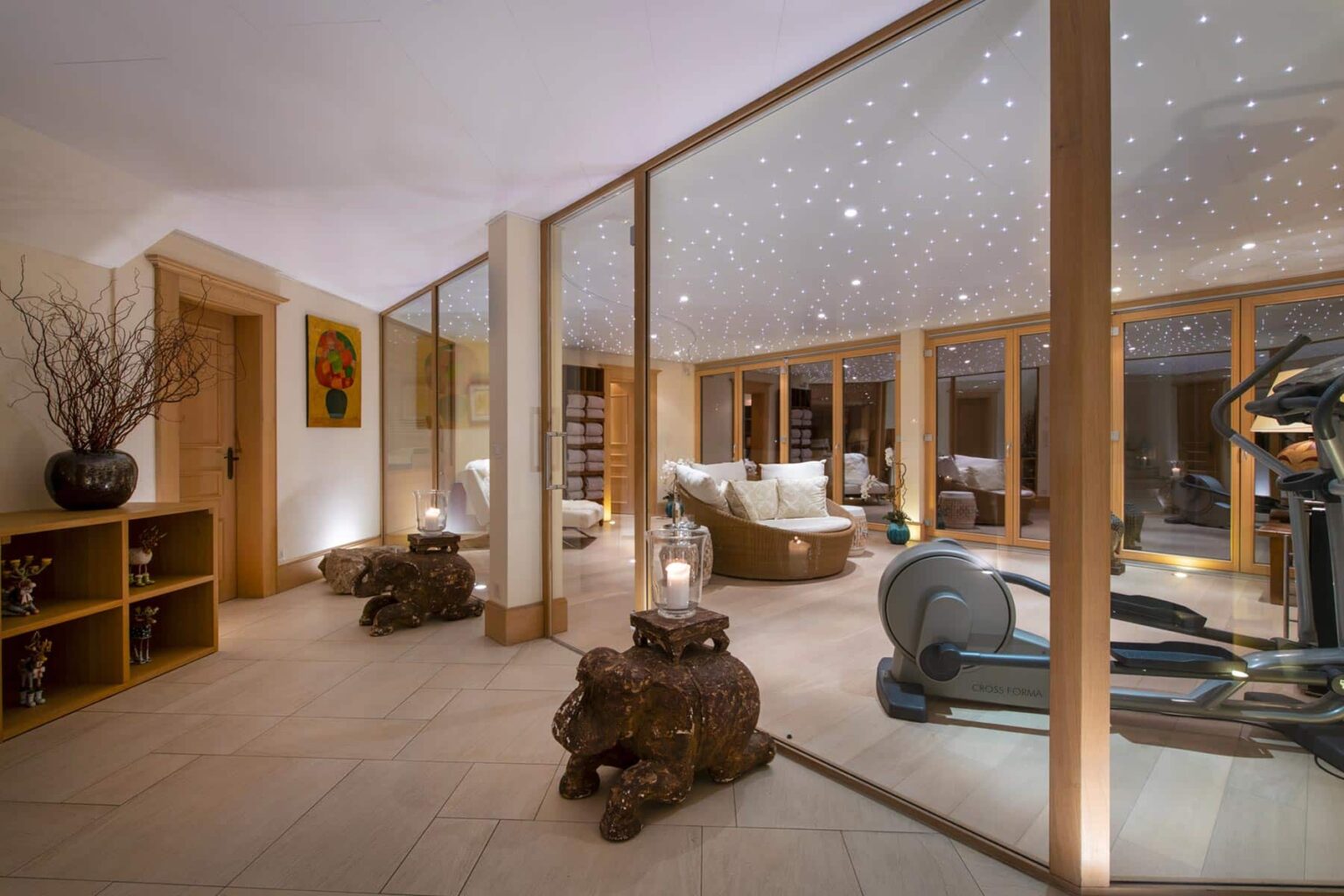 Home spa interior featuring a tranquil atmosphere with ambient lighting, wooden accents, and a fitness area. The space includes comfortable seating, decorative elements, and a serene color palette, ideal for relaxation and wellness. | Only on SopranoVillas