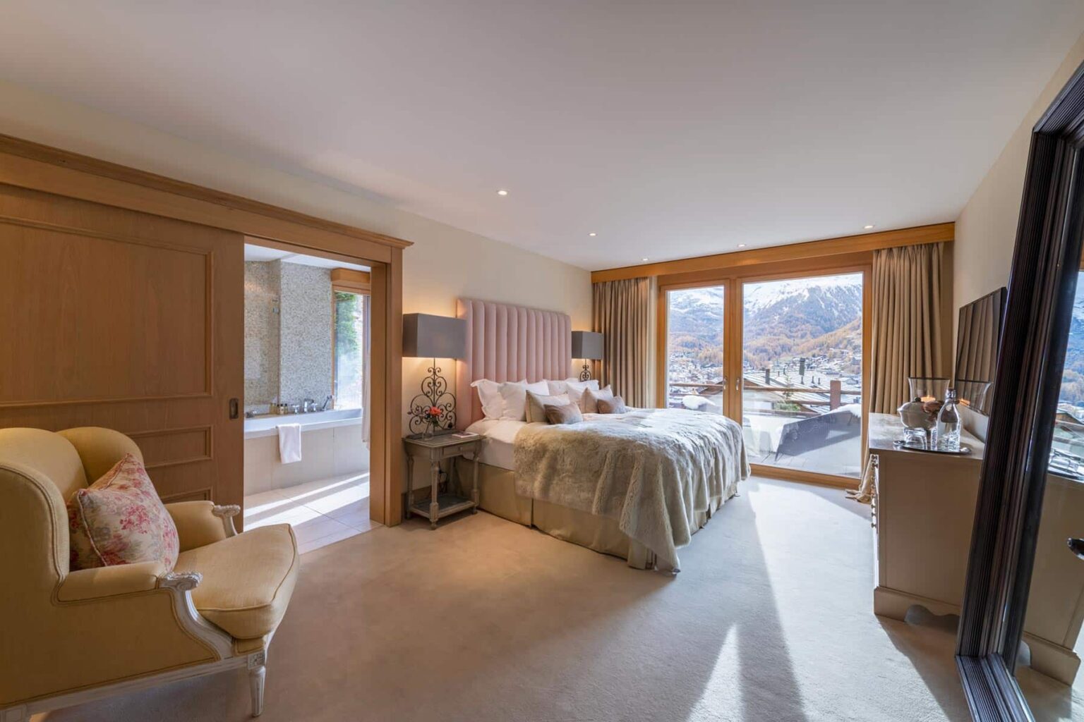 Luxurious hotel bedroom featuring a king-sized bed, elegant furnishings, and large windows showcasing a mountain view. The room includes a cozy seating area and modern amenities, creating a serene and inviting atmosphere. Perfect for a relaxing getaway. | Only on SopranoVillas
