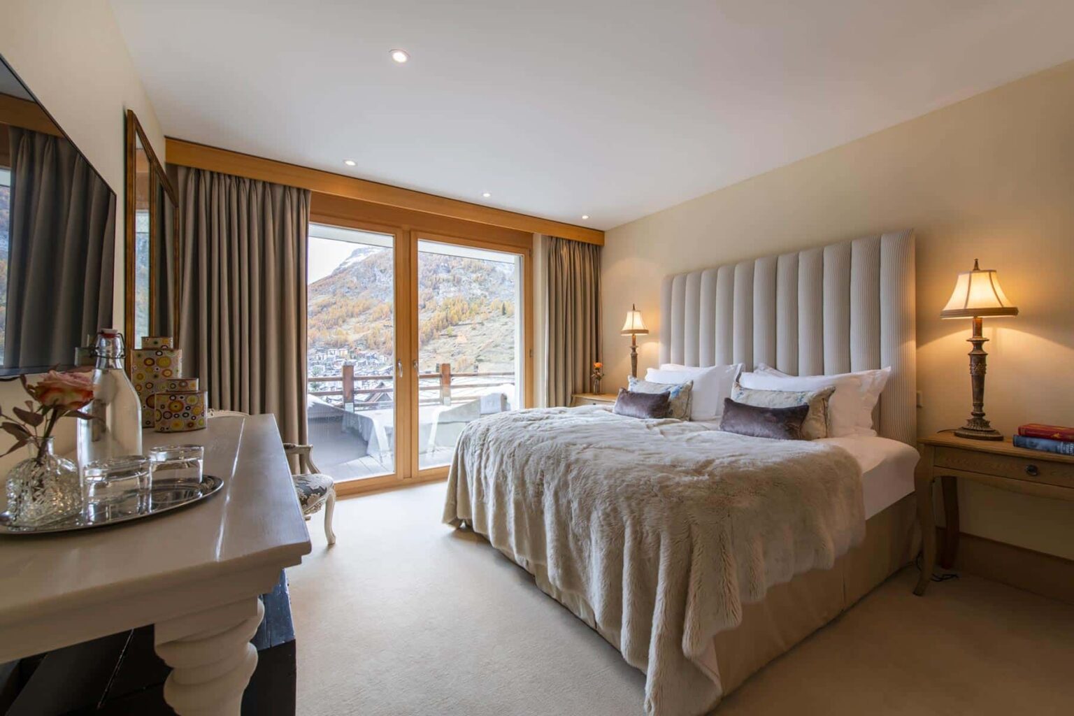 Luxurious hotel bedroom featuring a plush king-size bed, elegant decor, large windows with scenic views, and stylish bedside lamps. The room is designed for comfort and relaxation, perfect for a getaway. | Only on SopranoVillas