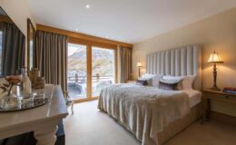 Luxurious hotel bedroom featuring a plush king-size bed, elegant decor, large windows with scenic views, and stylish bedside lamps. The room is designed for comfort and relaxation, perfect for a getaway.