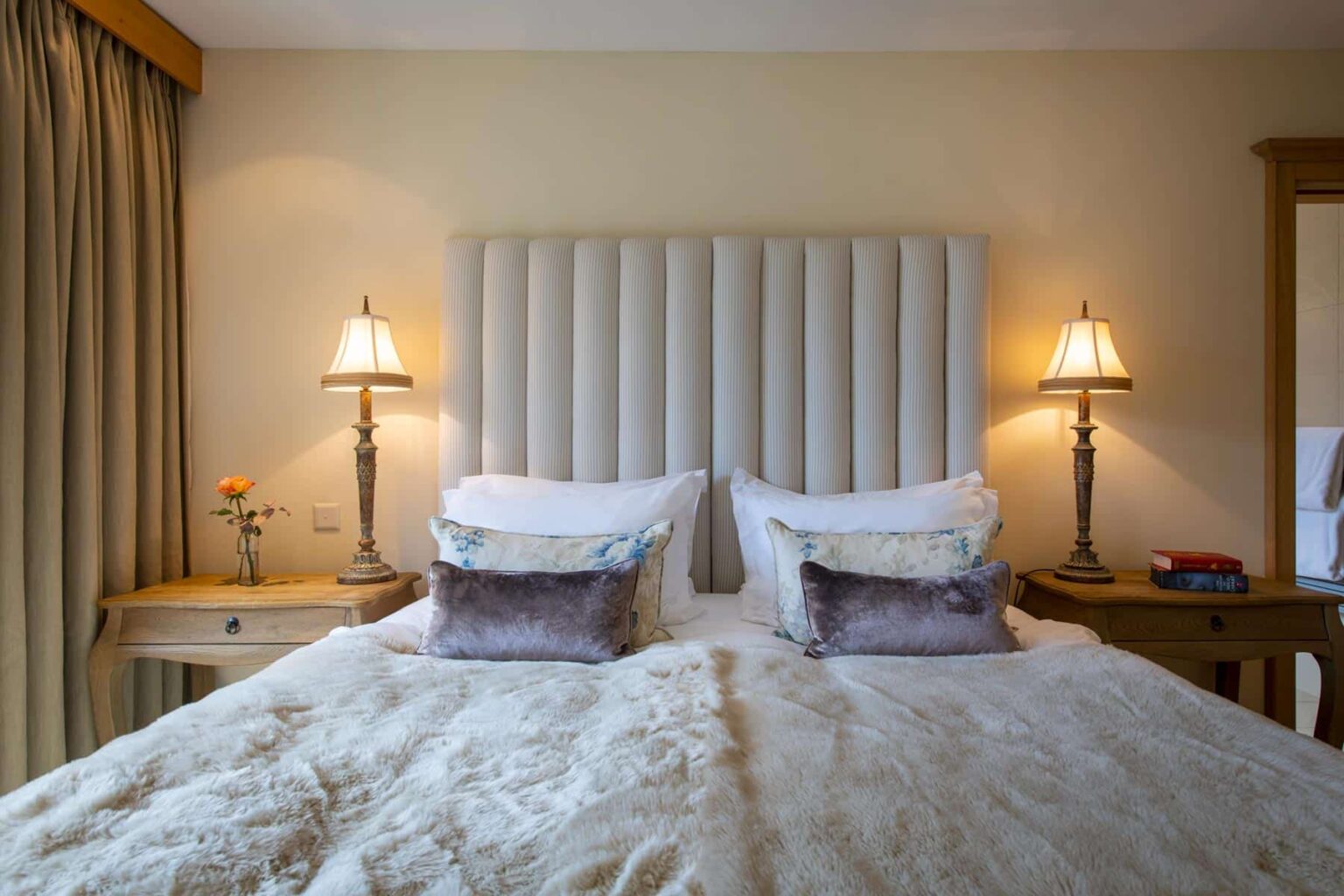 Cozy bedroom featuring a plush bed with decorative pillows, elegant bedside lamps, and a stylish headboard, creating a warm and inviting atmosphere. | Only on SopranoVillas