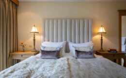Cozy bedroom featuring a plush bed with decorative pillows, elegant bedside lamps, and a stylish headboard, creating a warm and inviting atmosphere.