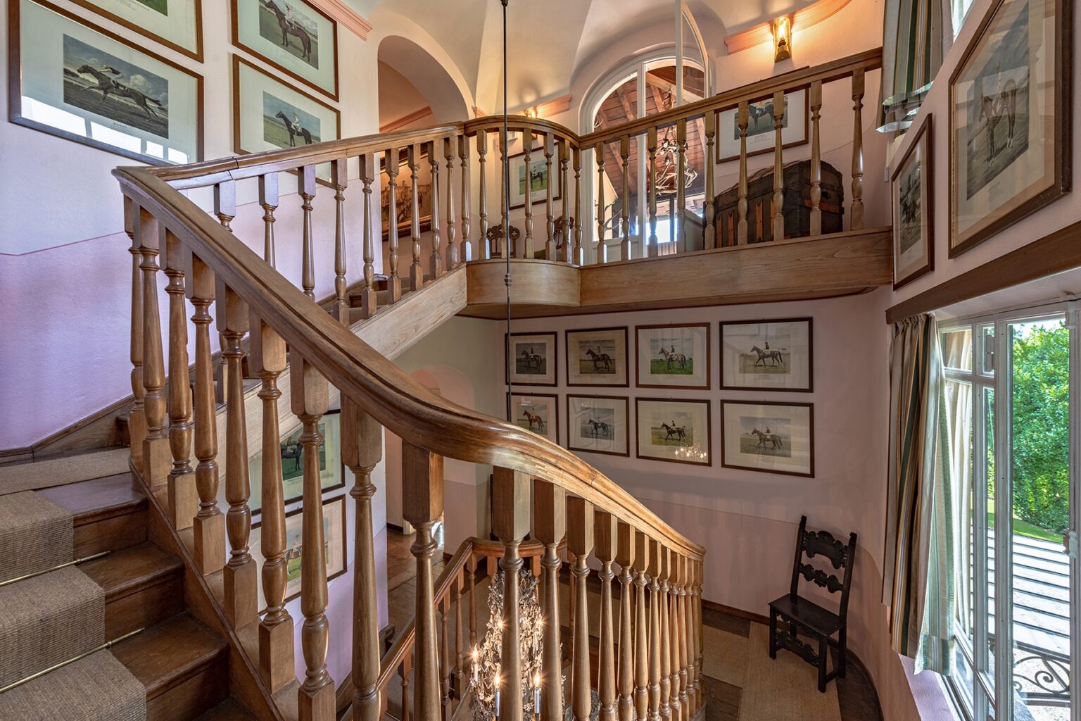 Elegant wooden staircase in a well-lit interior, adorned with framed artwork on the walls, showcasing a blend of classic design and natural light. | Only on SopranoVillas